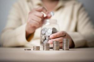 mujer trabajadora y un frasco lleno de monedas tailandesas. concepto de trabajar duro ahorrando más. foto