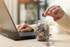 mujer trabajadora y un frasco lleno de monedas tailandesas. concepto de trabajar duro ahorrando más. foto