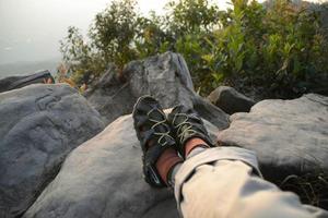 Someone shoes sit on rock for see view nature. photo