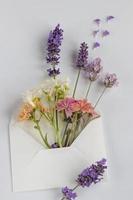 un pequeño ramo de varias flores en un sobre. feliz cumpleaños, día de san valentín, boda, concepto de tarjeta de felicitación del día de la madre. foto