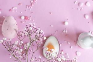 fondo de pascua con huevos de pascua de colores y flores florecientes sobre un fondo rosa. espacio de copia de pascua foto