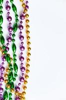 Mardi Gras background. Gold, green and purple beads on white background. Fat Tuesday symbol. photo