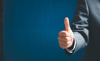 Close up of businesswoman showing raised thumbs at the camera as a gesture of recommendation or good choice. Professional support and service team demonstrates satisfaction and gives a positive. photo