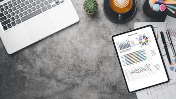 Tablet with charts and reports on office desk workplace. Top view flat lay photo