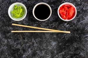 Set for sushi soy sauce ginger wasabi with chopstick on stone background photo