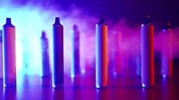 Lots of E-cigarettes and Vapes in Neon Lighting and Smoke. Concept of Bad Habits. Modern Alternative to Tobacco Products. Nicotine Addiction. Slow Motion. video