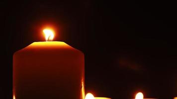las velas arden con una suave llama amarilla en la oscuridad. religión y concepto funerario. pena por los muertos. camara lenta. video