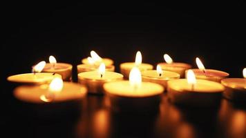 las velas arden con una suave llama amarilla en la oscuridad. religión y concepto funerario. pena por los muertos. camara lenta. video