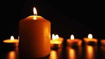 candele bruciare con un' morbido giallo fiamma nel il scuro. religione e funerale concetto. tristezza per il morto. lento movimento. video