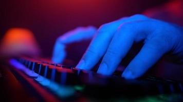 Close-up, Unrecognizable Man Using a Computer Keyboard to Code a Website in Neon Lighting. Hacker and Cybercrime or Cyberspace Concept. video