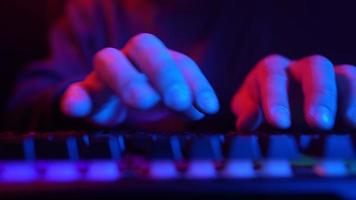 manlig händer skriver på en dator tangentbord i neon belysning. oigenkännlig kille arbetssätt på en bärbar dator på natt. begrepp av hackare och cyber brott eller cyberrymden. video