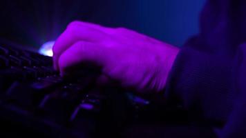 Close-up, Unrecognizable Man Using a Computer Keyboard to Code a Website in Neon Lighting. Hacker and Cybercrime or Cyberspace Concept. video