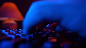 Close-up, Unrecognizable Man Using a Computer Keyboard to Code a Website in Neon Lighting. Hacker and Cybercrime or Cyberspace Concept. video