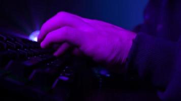 Close-up, Unrecognizable Man Using a Computer Keyboard to Code a Website in Neon Lighting. Hacker and Cybercrime or Cyberspace Concept. video