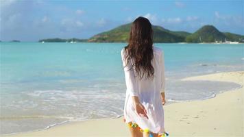 jovem e bonita se divertindo na beira-mar tropical. garota feliz andando na praia tropical de areia branca. câmera lenta video