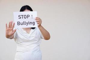 Closeup woman holds paper with text  STOP Bullying. Concept, campaign for anti bullying, body shaming or parody of others physical appearance. Stop violence. photo