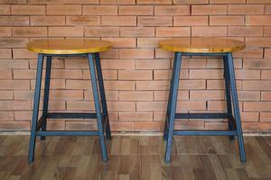 dos sillas de madera sobre fondo de pared de ladrillo foto