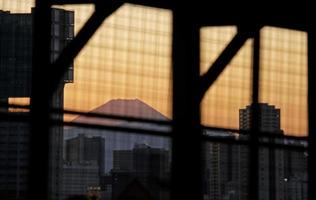 monte fuji durante la puesta de sol visto entre edificios en tokio, japón foto