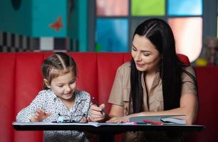 Mother helping her daughter with homework. Mother helping her daughter with homework. Happy childhood photo