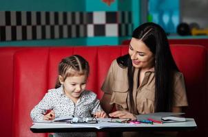 Mother helping her daughter with homework. Mother helping her daughter with homework. Happy childhood photo