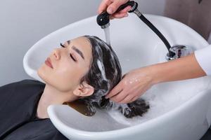 peluquero profesional lavando el cabello de una mujer joven en un salón de belleza. primer plano del cabello de la mujer en el salón de belleza, concepto de peinado foto