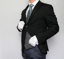 retrato de mayordomo en traje oscuro y guantes blancos de pie en elegante atención. concepto de personal del hotel y hospitalidad profesional. foto