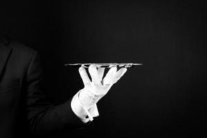 Isolated Image of White Gloved Hand Holding Silver Serving Tray on Black Background. Service Industry and Professional Hospitality. photo