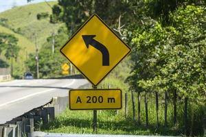 yellow road sign signaling a forward curve on a road photo