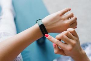 Young woman looks at a sports watch, checking performance or heart rate. Sports and fitness at home photo