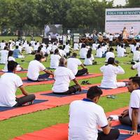 New Delhi, India, June 21 2022 - Group Yoga exercise session for people at Yamuna Sports Complex in Delhi on International Yoga Day, Big group of adults attending yoga class in cricket stadium photo