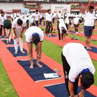 nueva delhi, india, 21 de junio de 2022 - sesión grupal de ejercicios de yoga para personas en el complejo deportivo yamuna en delhi el día internacional del yoga, gran grupo de adultos que asisten a clases de yoga en el estadio de cricket foto