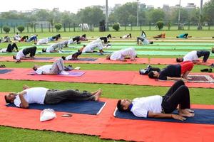 New Delhi, India, June 21 2022 - Group Yoga exercise session for people at Yamuna Sports Complex in Delhi on International Yoga Day, Big group of adults attending yoga class in cricket stadium photo