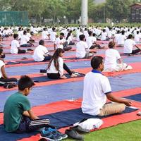 New Delhi, India, June 21 2022 - Group Yoga exercise session for people at Yamuna Sports Complex in Delhi on International Yoga Day, Big group of adults attending yoga class in cricket stadium photo