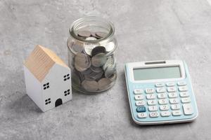 modelo de una casa de madera, calculadora de monedas. concepto de ahorrar dinero para un futuro hogar.