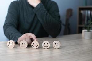 Hand of a businessman chooses a smile face on wood block circle.Customer service experience and business satisfaction survey.rating very impressed.Satisfaction survey concept. photo