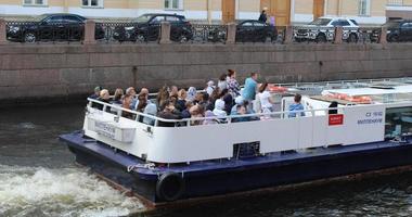 Sankt Petersburg Russia, 06 07 2022 tour boat full of tourists going up the Neva river. City island in background. photo