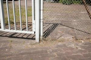 hole in the metal mesh of the chain-link fence, someone tore it open and entered the territory photo