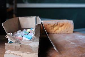 Lots of colorful chalk pieces in a torn cardboard box. photo