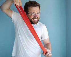 Positive man exercising with elastic band. Healthy and active lifestyle concept. photo