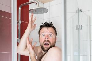 Man in the shower, in which the water stopped flowing due to a breaking or due to an energy crisis. photo