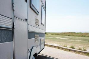 mobile home stands on the seashore near the road photo