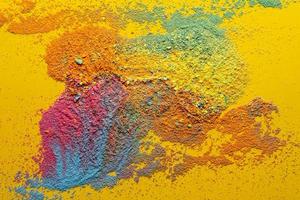 Mixture of multicolored powder is scattered randomly on a yellow background. Copy space. Abstract texture. Top view. photo