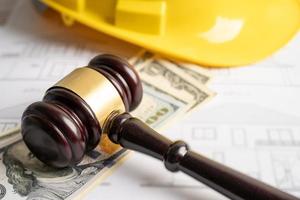 Architectural house plan project blueprint and Judge gavel hammer with yellow helmet and US dollar banknotes, Engineer and construction law and justice. photo