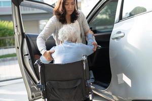 Asian senior or elderly old lady woman patient sitting on wheelchair prepare get to her car, healthy strong medical concept. photo