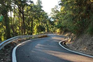 calle camino curvo hacia abajo colina montaña en el bosque foto