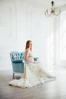 red-haired pregnant young girl in a blue armchair photo