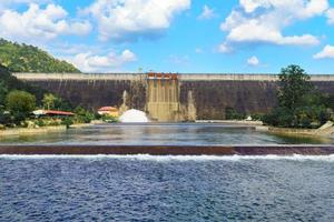Large water reservoir dam wall releasing water with beautiful sky photo