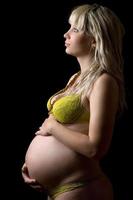 Pregnant girl in yellow lingerie. Isolated photo