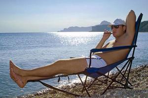 The young man with a cigar has a rest on seacoast photo