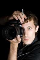 The young man - photographer behind work. Isolated on a black background photo